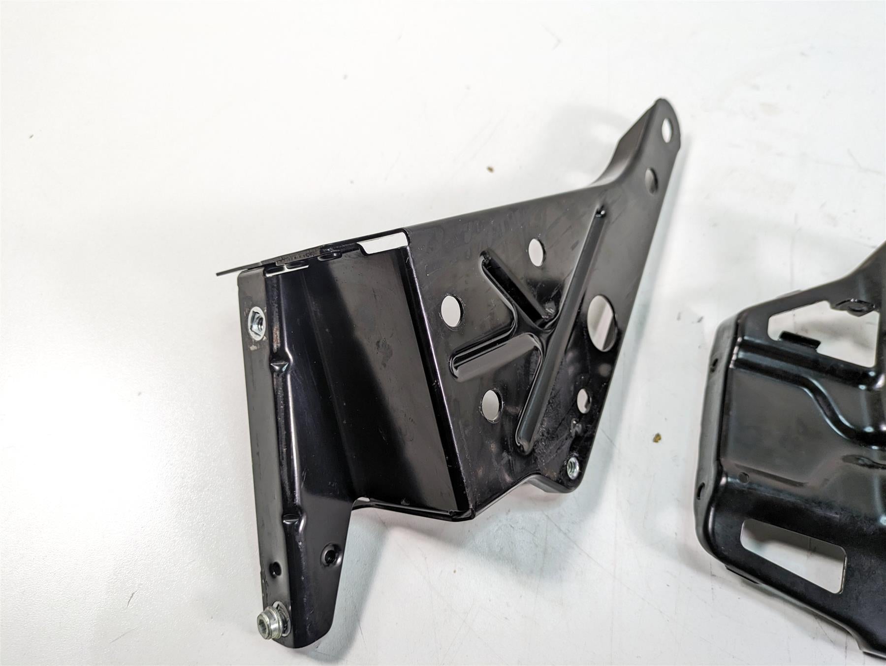 Black metal motorcycle bracket part on white background, available at Mototech271