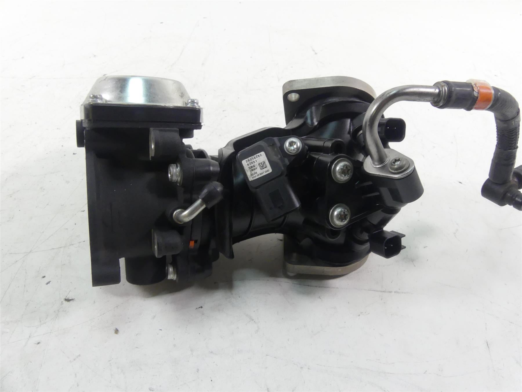 Used motorcycle throttle body with attached wiring and metal hose on white background, available at Mototech271