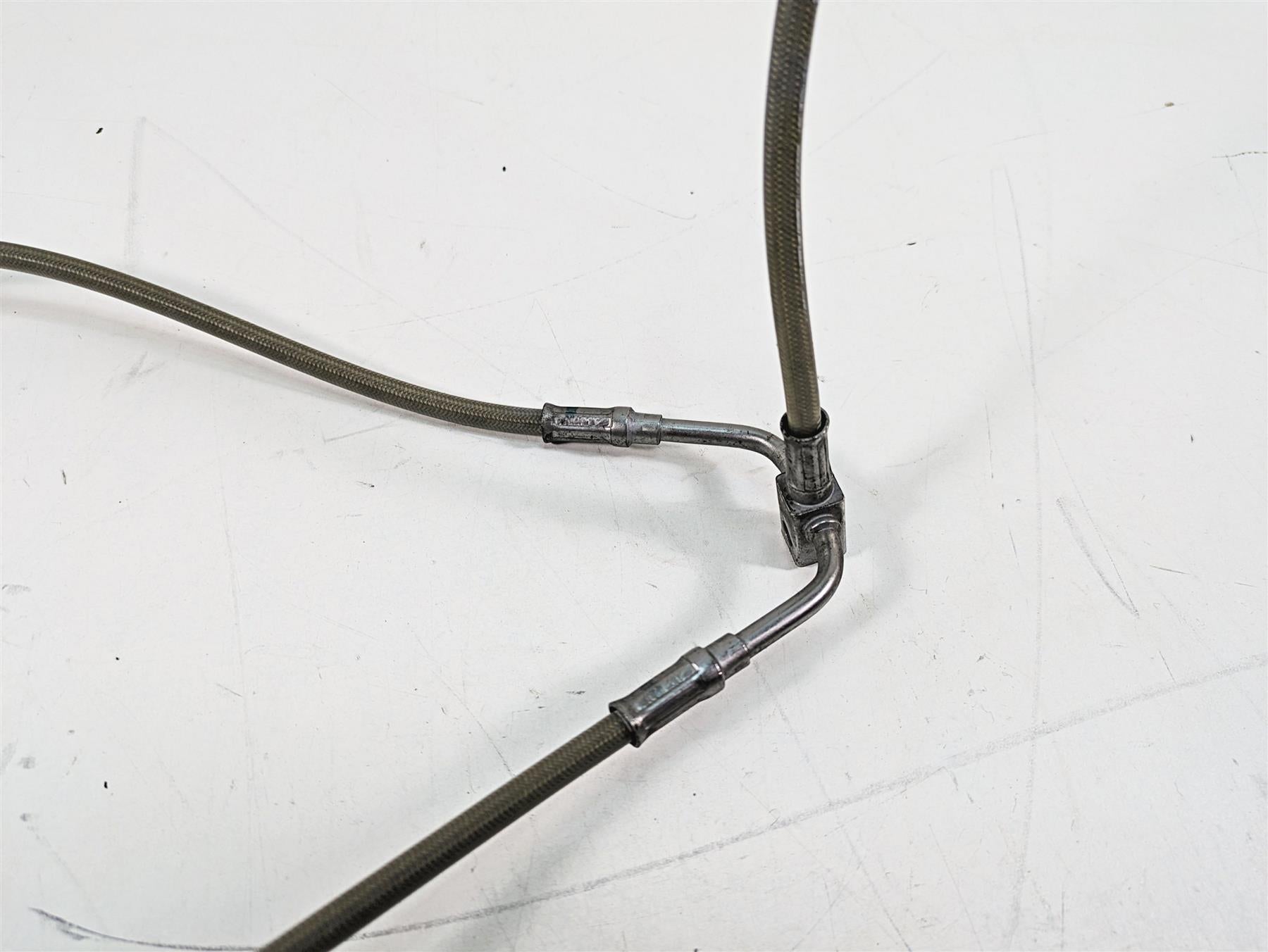 Used motorcycle braided brake line splitter with metal fittings on white background, available at Mototech271