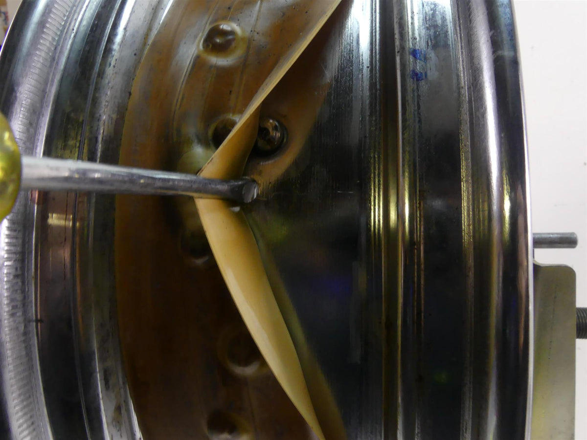 Close-up of motorcycle wheel rim with rim strip and screwdriver, available at Mototech271