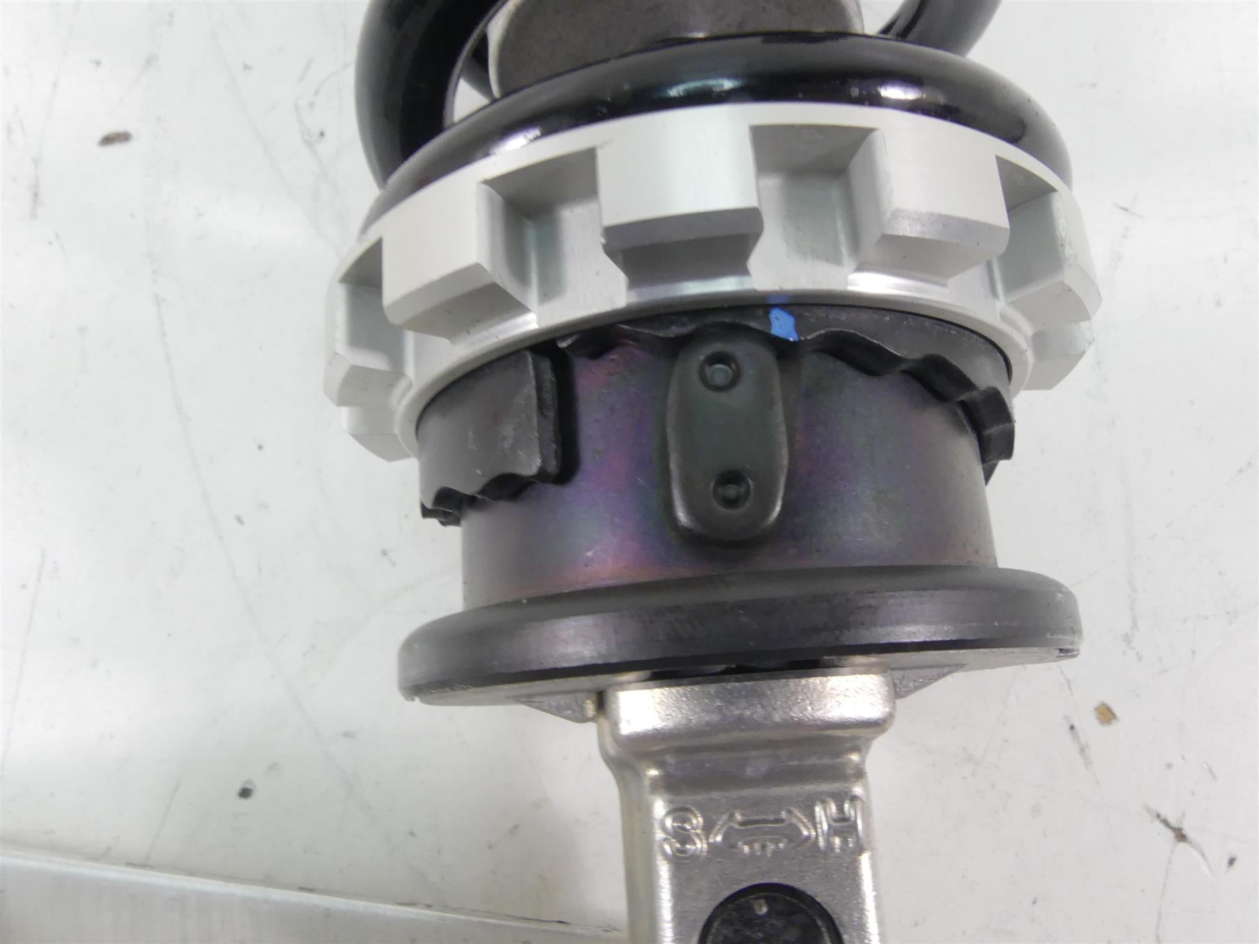 Close-up of a used motorcycle shock absorber coil spring on white background, available at Mototech271