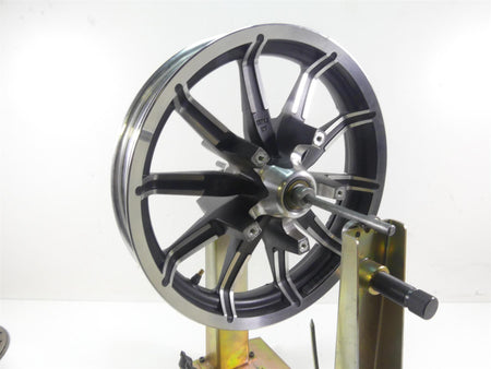Black alloy motorcycle wheel rim with spokes on truing stand, available at Mototech271