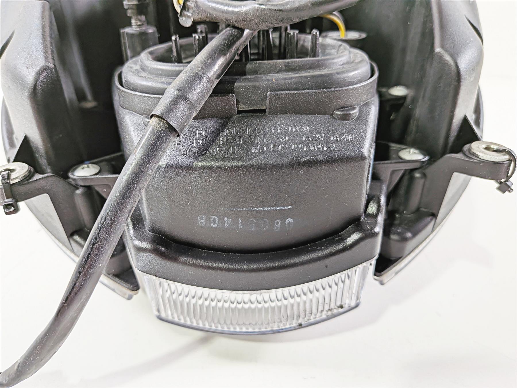 Used motorcycle headlight assembly with wiring and mounting brackets, close-up view