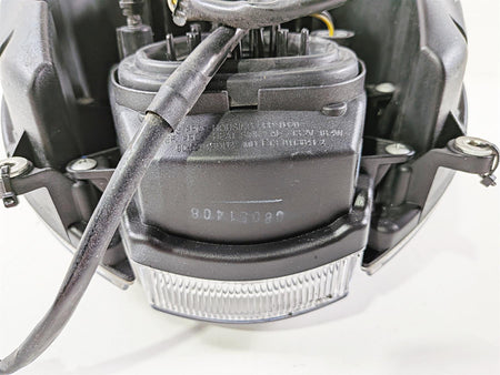 Used motorcycle headlight assembly with wiring and mounting brackets, close-up view