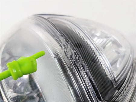 Close-up of used motorcycle headlight lens with green pointer indicating detail