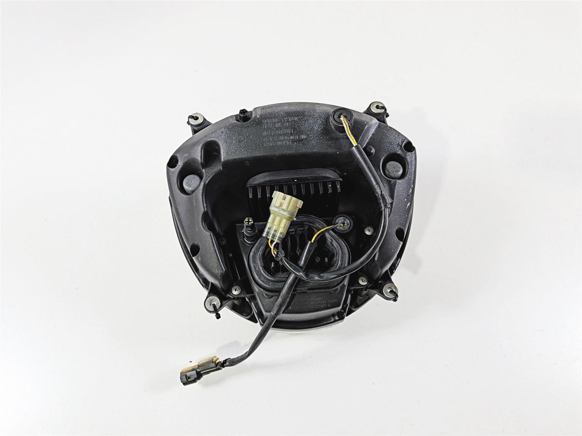 Used motorcycle headlight assembly with wiring harness on white background