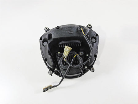 Used motorcycle headlight assembly with wiring harness on white background