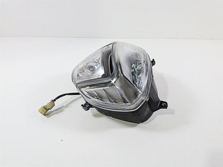 Used motorcycle headlight assembly with wiring connector on white background