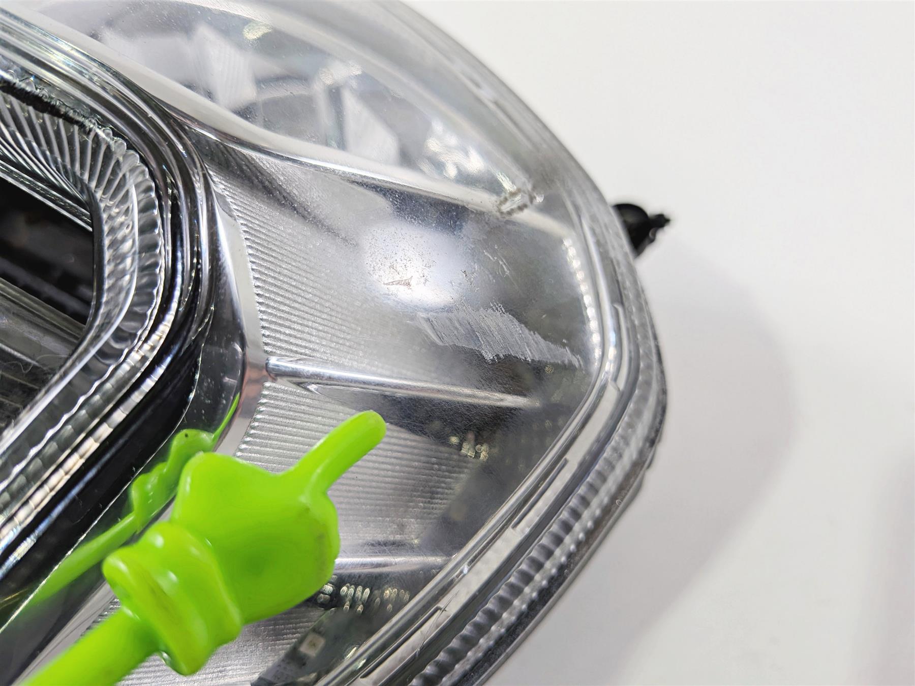 Close-up of used motorcycle headlight lens with visible scuffs and scratches