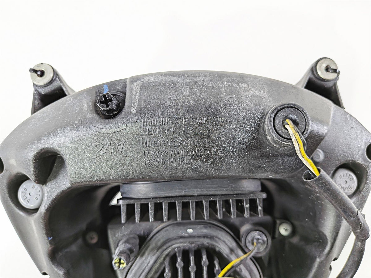 Close-up of a used motorcycle headlight housing with wiring and mounting points visible