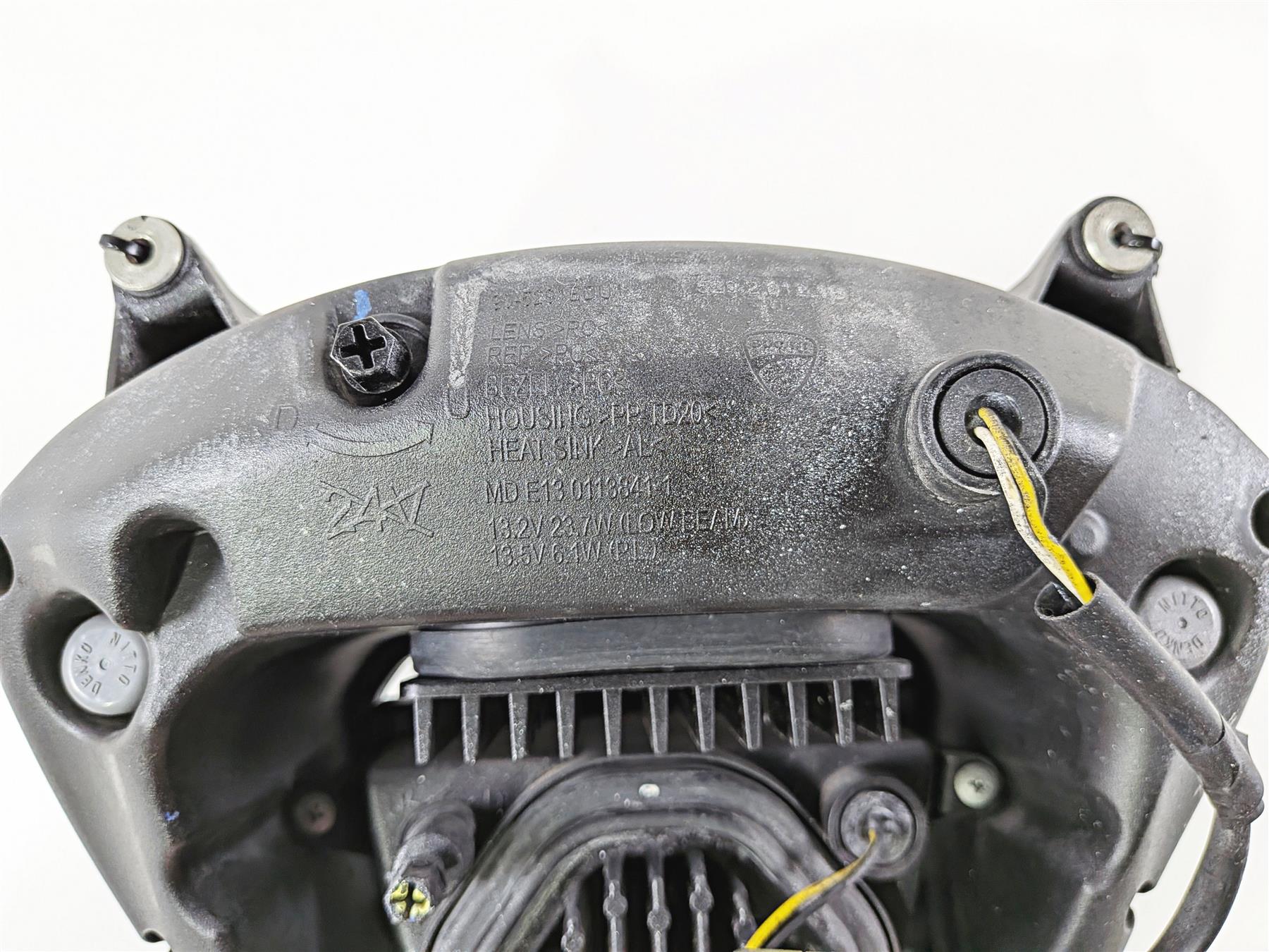 Close-up of a used motorcycle headlight housing with wiring and mounting points visible