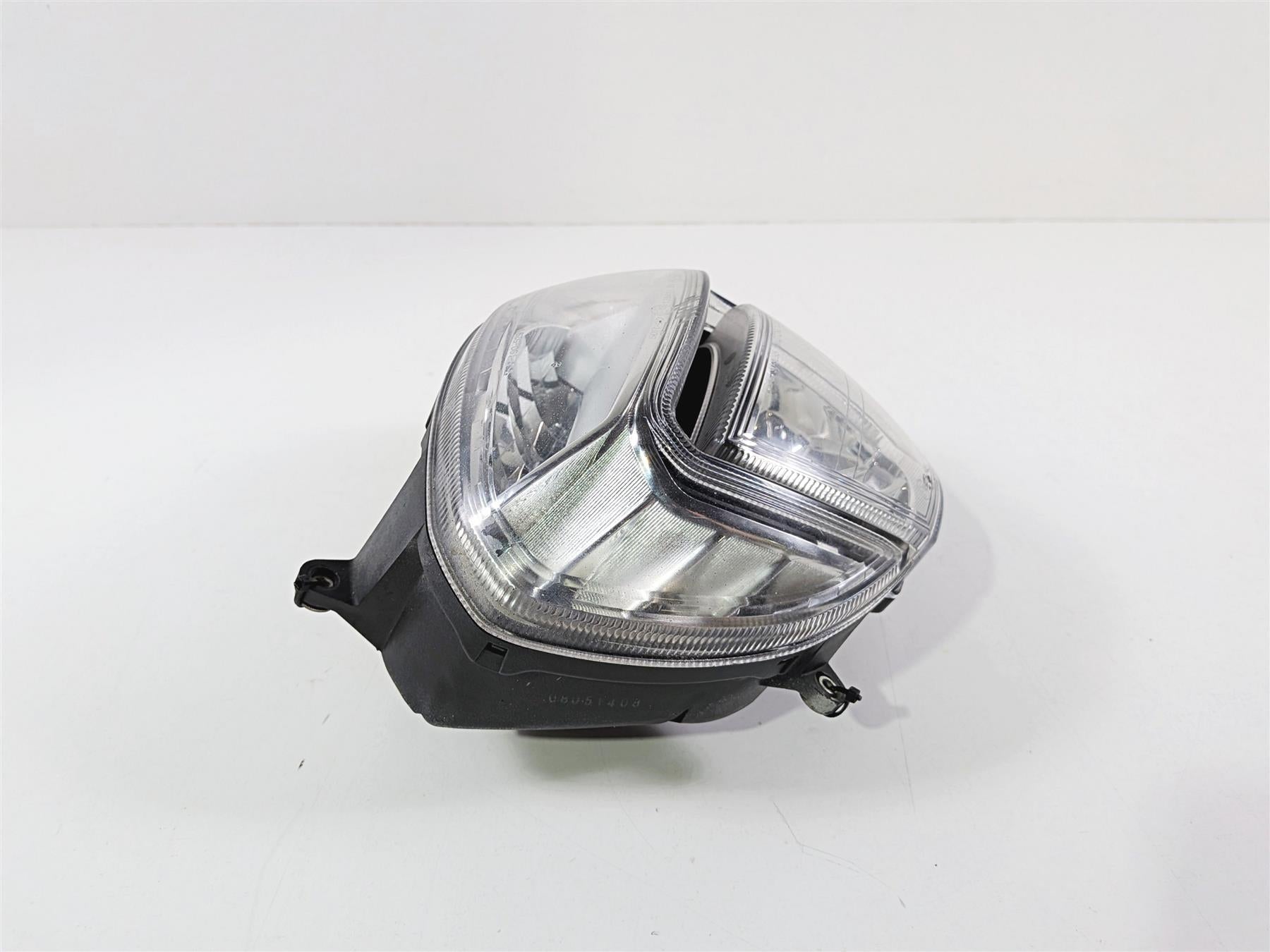 used motorcycle headlight assembly with clear lens and black housing on white background