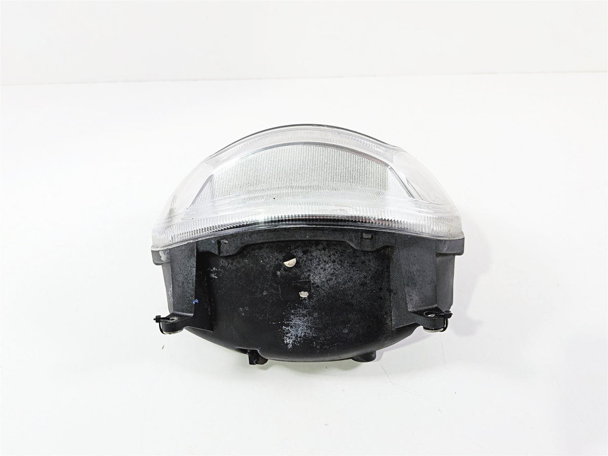 Used motorcycle headlight assembly with clear lens on white background