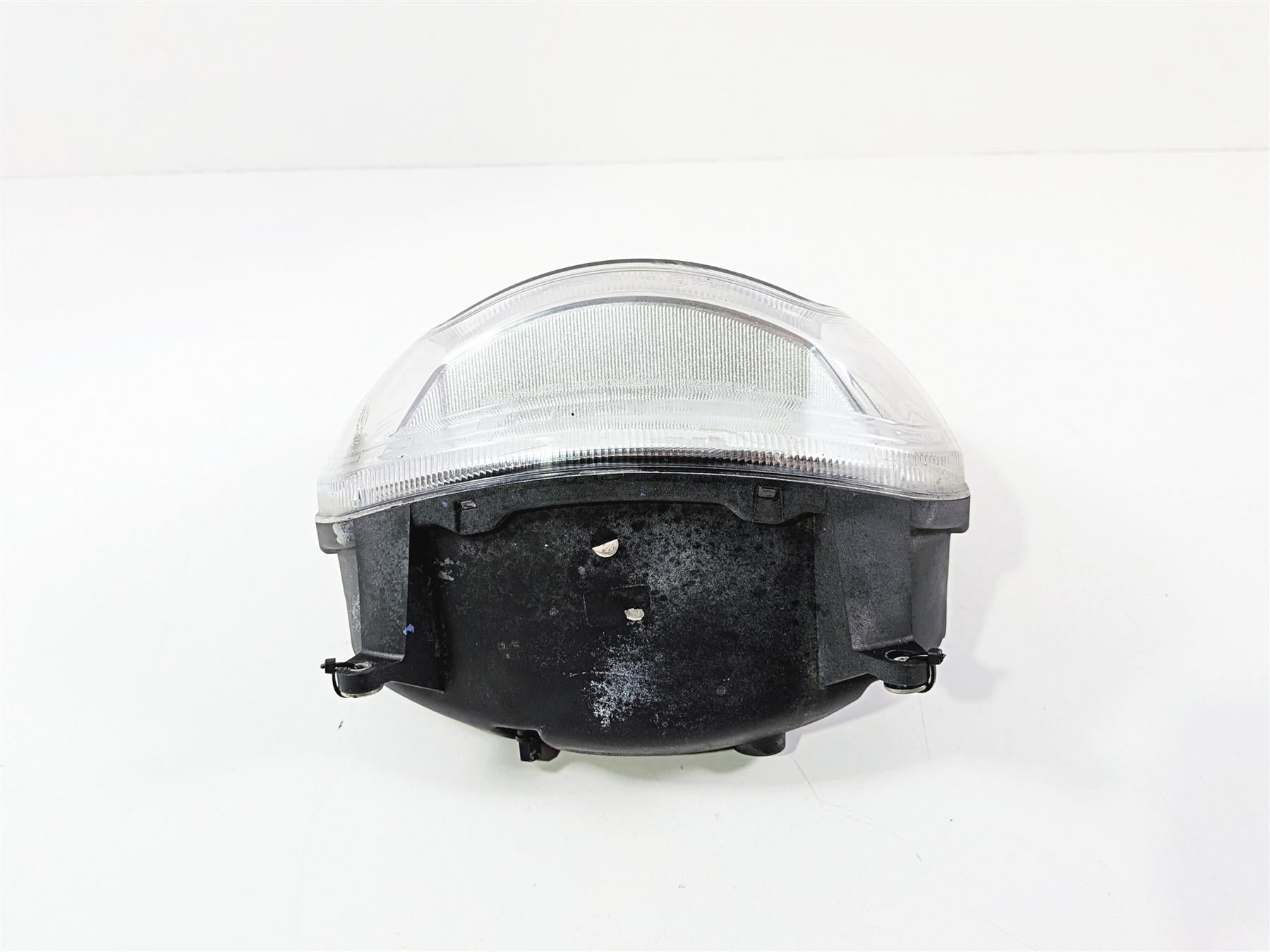Used motorcycle headlight assembly with clear lens on white background